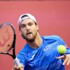 João Sousa um dos maiores tenistas portugueses de sempre a jogar uma partida de ténis com um boné branco e camisola azul