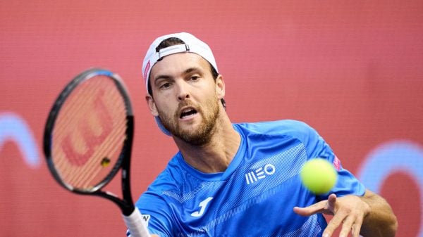João Sousa um dos maiores tenistas portugueses de sempre a jogar uma partida de ténis com um boné branco e camisola azul